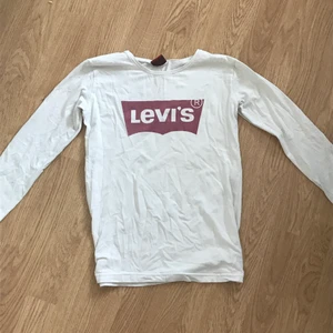 Levi’s,vitt långärmad med ett rött tryck - Vitt långärmad levi’s tröja med ett rött tryck, passformen är till en XS-158 men den skulle både passa till en S/M också beroende hur man vill att den ska sitta på en, ärmarna är ganska korta så därför skulle den sitta komplett till en XS/S tror jag