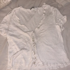 NA-KD - Vit T-shirt med vit/silvriga knapar i mitten. Andvänd 2 gånger då den är för stor på mig. Man kan också ha den som kofta