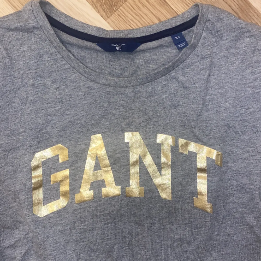 Grå T-shirt från GANT med guldigt tryck. Storlek XS. Knappt använd!. T-shirts.