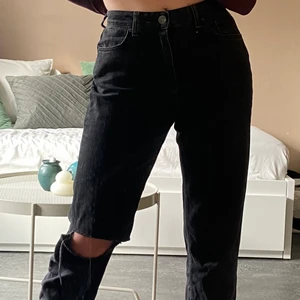 Svarta jeans  - Svarta jeans med hål vi knäet. Lite baggy eller kan man para den med ett bälte för ha den tight runt midjan. 