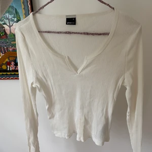 Vit långärmad topp - Vore långärmad T-shirt med djup hals. Tröjan är från Gina och är storlek M. Den är helt onanvänd då jag köpt en för stor storlek. T-shirten är ganska bred och en lite kortare modell! 