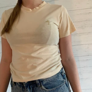 Beige T-shirt  - Beige T-shirt från and other stories med guldig broderad palm på bröstet. Knappt använd och bra skick. Kika gärna in övriga toppar som jag lagt ut så kanske vi kan fixa ett packetpris. 