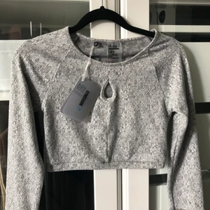 GymShark Grå Topp - Helt oanvänd träningstopp beställd från GymShark. Croppad passform, lite tjockare tyg (ej genomskinlig) med hål för tummarna. Säljer då den aldrig kommit till användning. Kan mötas i Uppsala eller skickas (frakt 45kr samt 20kr kostnadstillägg om safepay önskas). Fler plagg från GymShark i min profil.