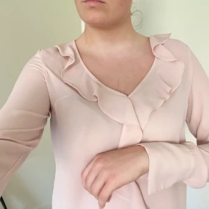 Rosa blus med volanger - En rosa blus mes volanger som har använts väl men med försiktighet! Fint skick och har en fin och smäck passform😍