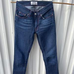 Mörkblå jeans med röda sömmar, från acne studios Storlek 28/32. Innerbenslängd: 77 cm. Midjemått: 34 cm rakt över. 