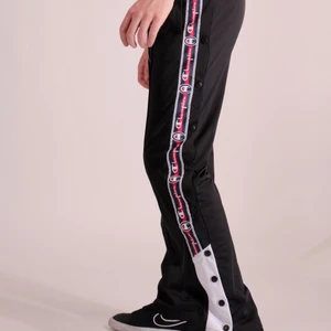 Champion Longpants - Svarta byxor med öppningsbara knappar längst benen. Byxorna är i fint skick 
