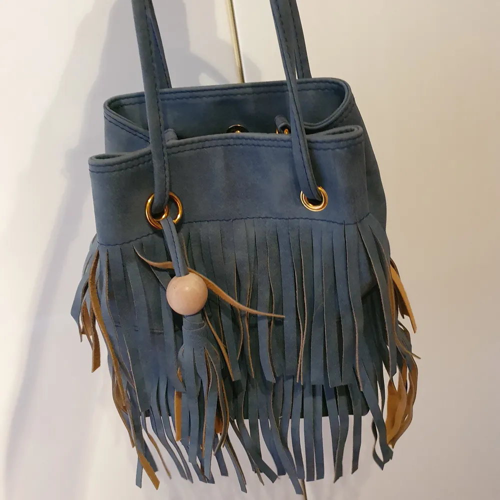 En blå väska med fransar på ena sidan säljes pga använder den inte. Kostar 150 +60 kr frakt.. Väskor.