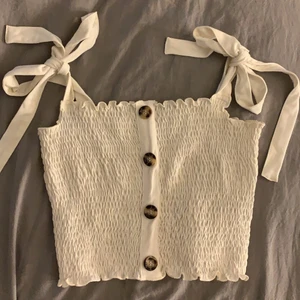 Topp från Nakd - Vit topp med knappar från Pamela x Nakd. Knappt använt och i bra skick. Köparen står för frakt.