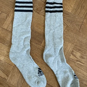 Adidas strumpor - Ett par gråa ångstrumpor med svarta ränder från adidas 