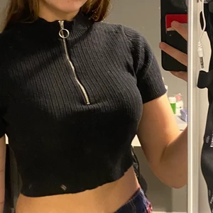 Svart tröja med dragkedja  - Snygg, svart, cropped tröja med dragkedja från Gina Tricot i storlek S. Säljs inte längre i butik. Använd bara några få gånger. Passar perfekt nu till sommaren. Har inga fläckar (spegeln är smutsig) och inga hål. Som i nyskick. Frakten ingår i priset!! Tveka inte vid frågor🥰 Priset kan diskuteras!