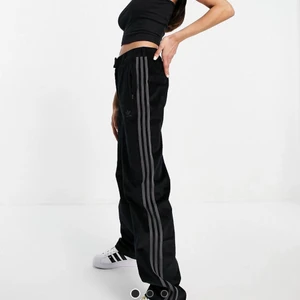 Adidas Comfy Cors  - Svarta kostymbyxor i Manchester med hög midja och vida ben. Passar perfekt på någon som är mellan 165-175. Använda 1 gång och säljs då jag inte får dom till någon användning. Superfina och jätte sköna!  (Bilder lånade från ASOS). Bud kan ske i kommentarerna, eller på privatmeddelande!