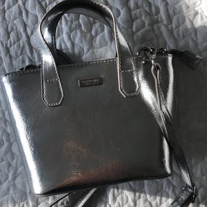 Väska från don donna  - Jättefin silvrig väska från don Donna. Är använd ett fåttal gånger och är i bra skicka. Köpte för 400kr och säljer för 200kr + 40kr frakt.