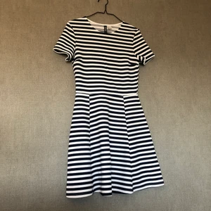 Sommarklänning m. snurr  - • Randig klänning i vitt & marinblått • Storlek: 36 • 96% polyester & 4% elastan • Knappt använt, fint skick! Legat nerpackad en längre tid så upptvättning rekommenderas. • +Frakt: 51kr spårbart  