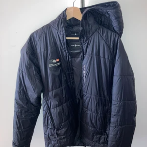 Sail Racing Dunjacka - 6/10 skick, den har en skada på ryggen som man ser på bilden. Annars är den i bra skick. Köpte för lite över 2000, säljer för 299