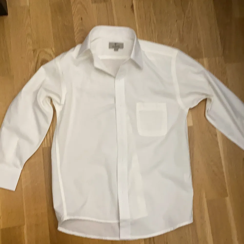 En fin vit skjorta till din bror eller din son vid 9-10 års åldern. Använd 1 gång för länge sen. Har knappar både på framsidan och handledarna. Helt vanlig på baksidan. Jättefin skjorta. . Skjortor.