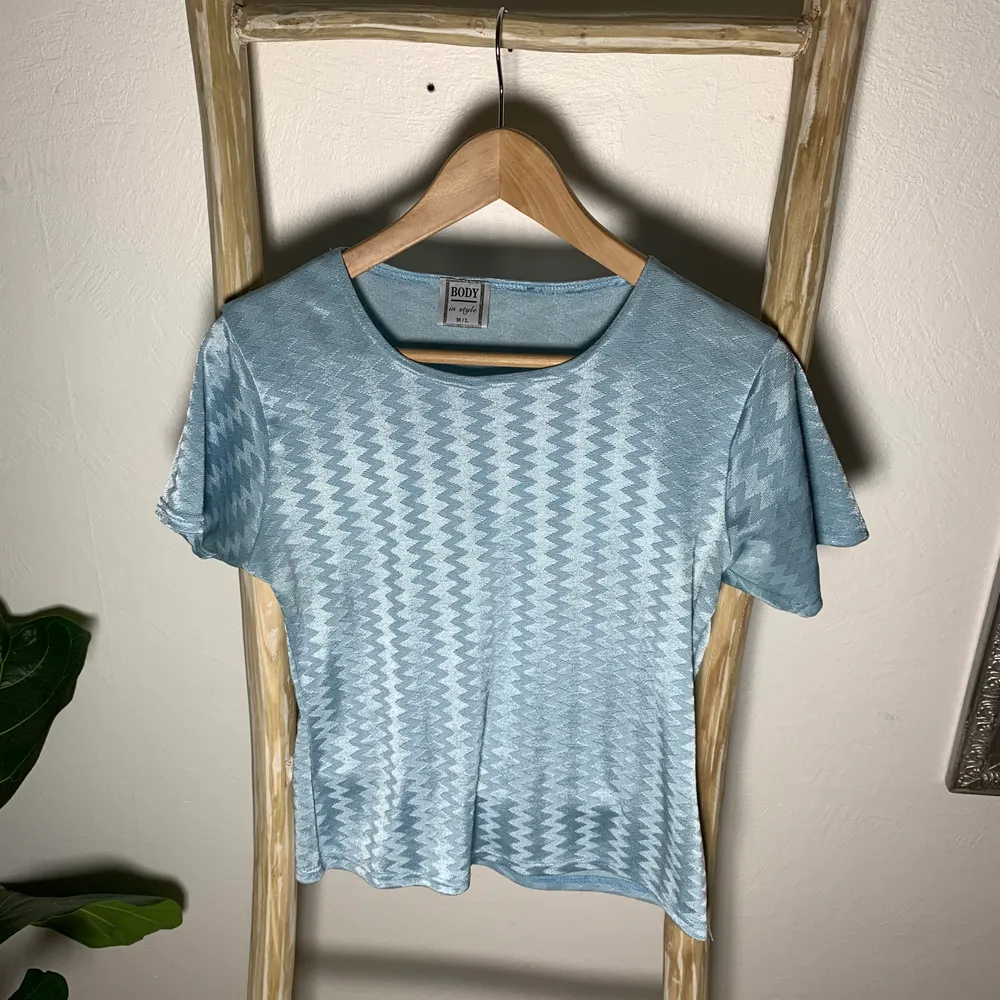 En blå tshirt som har ett glansigt, mönstrat material. Den är stretchig och knappt använd. Så fin på sommaren! Passar XS-L.. T-shirts.