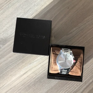 Michael Kors Klocka  - Jättefin Michael Kors klocka i silver, behöver byta klockbatteri då den legat i min byrå i 3 år.  Bra skick! Säljes pga flyt & använder ej. Frakt tillkommer 🚚