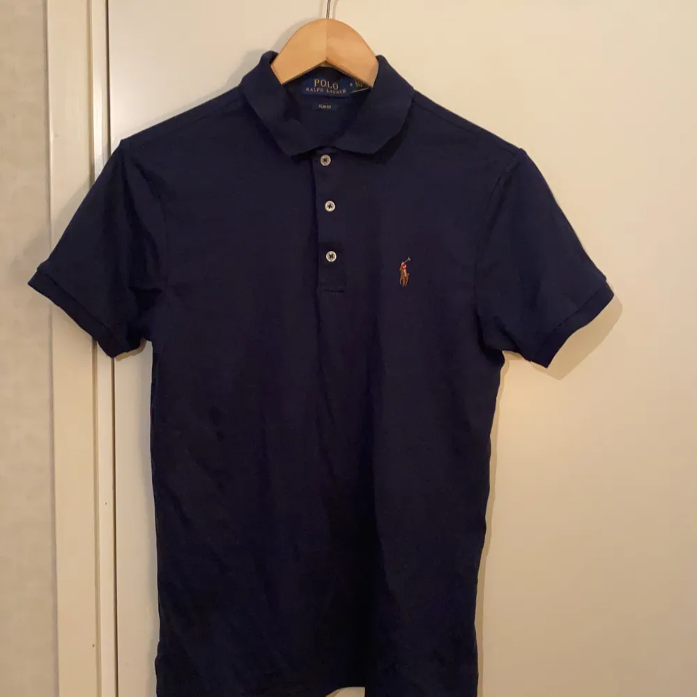 Marinblå kortärmad piké från Polo Ralph Lauren som är i nyskick, använd några gånger. Broderad logga på vänster bröst. PRIS KAN DISKUTERAS!!!. Övrigt.