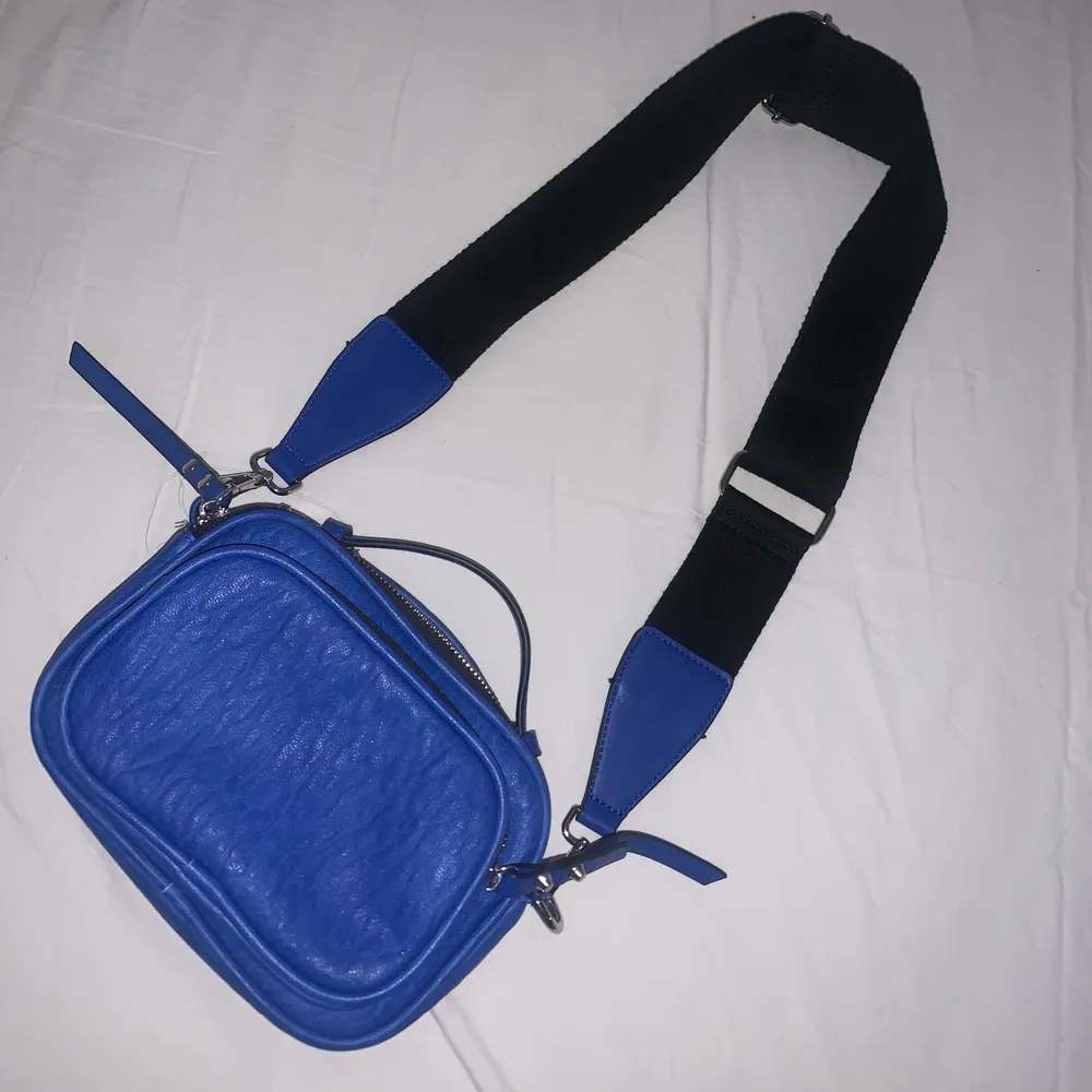 Säljer denna jättefina blåa väskan då jag aldrig har hittat ett tillfälle att använda den🦋 Med väskan kommer ett justerbart band. Nyskick!. Väskor.