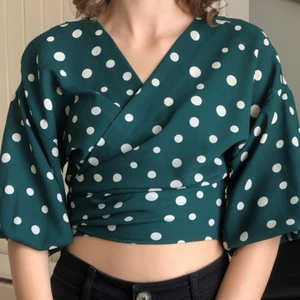 Prickig grön omlottblus - Grön prickig omlottblus från Bikbok. Går att knyta både fram och bak som ni ser på bilderna. Storlek XS. Skriv för mer bilder!