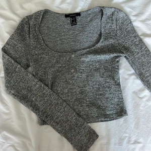 Gråmelerad tröja med knappar därfram  - Nyskick och knappt använd då stl är för stor. Köptes på Forever 21 i Japan.