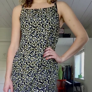 Klänning från primarkt strl. 36 - Mjuk svart klänning med vita och gula blommor, aldrig använd. 