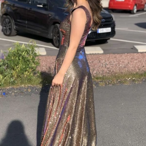 Balklänning/festklänning/långklänning  - Säljer min fina balklänning, den är i fint skick. Den reflekterar massa fina färger och glittrar (särskilt i solen). Klänningen har ”inbyggda” kupor så man måste inte ha bh under om man inte vill. Storleken motsvarar 32/34 eller Xxs/Xs. Är 162-163 cm och har 10cm klackar på bilden. Nypris 2000kr, säljer den för 800kr + frakt, men priset går att diskutera vid snabb affär. Hör av er vid frågor! 