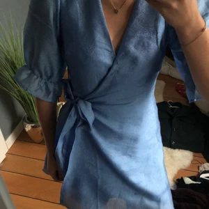 Blå wrapklänning - Säljer min blåa wrapklänning som igentligen är lång men som jag själv sytt upp. Dock är knappen sönder men den har ingen super betydande roll
