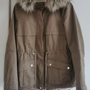 Jacka med pälskrage från H&M - Ljusbrun jacka med pälskrage från H&M:s Divided avdelning. Mjukt teddytyg på insidan. Storlek 40 men aningen liten i storleken. 