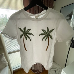 Vit T-shirt  - Supersöt T-shirt med palmer över brösten, använd väldigt få gånger då jag ändrade mig (ca 2-4 gånger) nypris 200kr. Betalning via swish frakt bestämmer du! Frakt ingår inte i priset