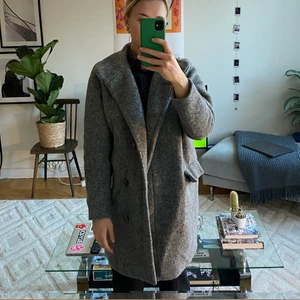 Samsoe Samsoe Ullkappa - Fin grå kappa från Samsoe Samsoe i modell Hoffman. Storlek XS, men lite oversize så passar en S. Inköpspris ca. 2500 kr. Använd men i fint skick. Hälla som man hänger har gått av en gång men är sydd och inga märken från det syns på insidan.