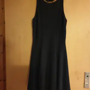Snygg svart klänning med guld detal.längd från axel 90 cm