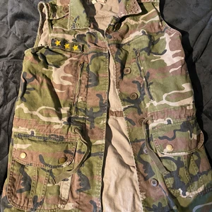Trendig jeans väst - Snygg väst som går ner lite under höfterna. Går att spänna i midjan så man får lite mera form. Militär kamouflage i färg och riktigt snygg till ett par blåa jeans. Aldrig använt och vet ej vart jag köpt den, säljer för 250kr och kunden står för frakt🥰 hör av dig om du vill ha mer info eller bilder. Priset kan diskuteras:)