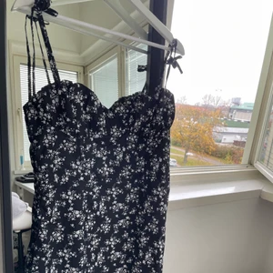 Svart blommig klänning - Superfin svart klänning med vita söta blommor på! Anpassningsbara band pga man knyter sj efter hur man vill ha dem❤️