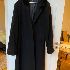 Ullkappa Svart retro - Retro svart ullkappa i 80% ull. Huva och krage i fuskpäls samt gömd knäppning. Kan mötas upp eller skicka på posten(köpare betalar frakten). Samfraktar gärna om du köper flera plagg!