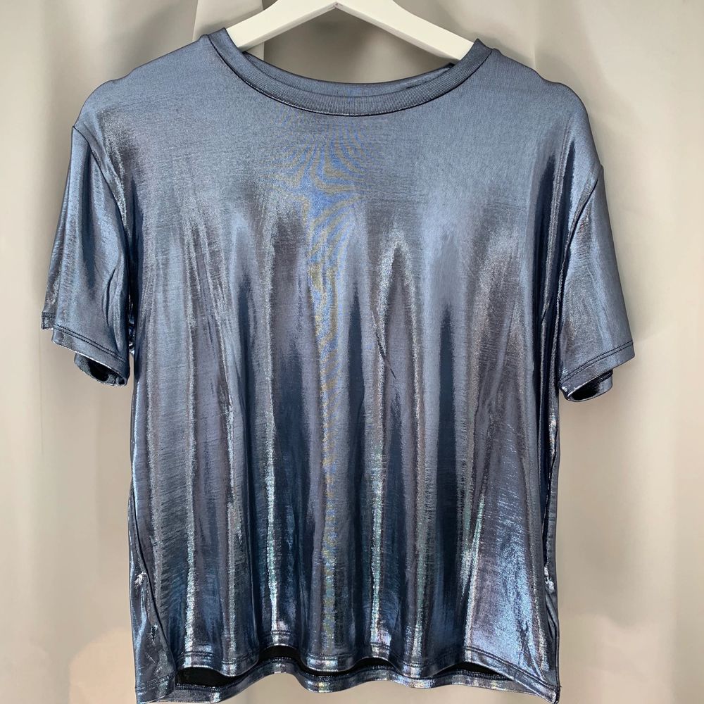 Säljer min silvrig/glansiga t-shirt från hm, aldrig kommit till användning så den är i nyttskick!! köparen står för frakten!😘. T-shirts.