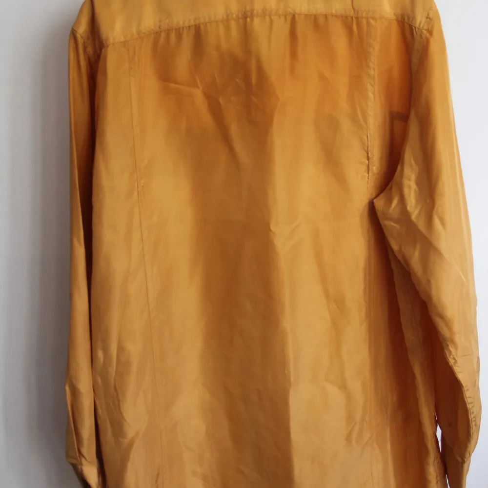 Lindex 42/44. Oversized brandgul skjorta i 100 silke. Superfin färg!! Finns en liten reva bak på ryggen som jag kan skicka bild på om man är intresserad. Säljer billigt🥰. Skjortor.