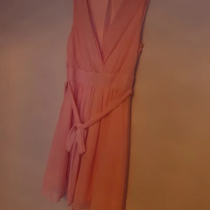 Laxrosa klänning med snörning/knytning - Klänning med knytning storlek 38 men jag är storlek 40 och kan ha den. Fint skick då jag inte använt den så mycket 