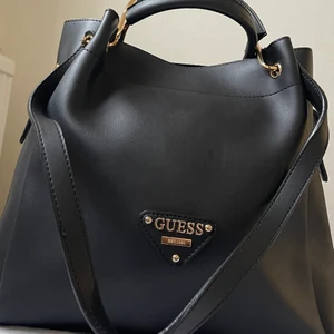 Bucket väska - Guess Tote Väska med guld detaljer. Minimal spår av användning. Nypris 2300kr