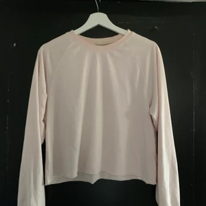 Långärmad rosa törja - Den är rosa de är den men den är rätt ljus, sömmarna går från nacken till armhålan så även om den sitter som en vanlig tröja i vanliga fall så kan den verka croped när man lyfter på armarna.