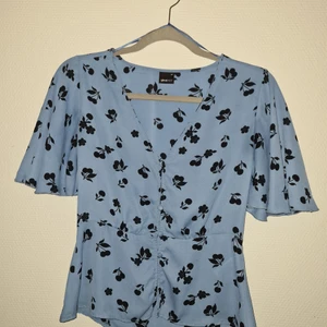 Topp Ginatricot strl 34 - Blå topp från Ginatricot i storlek 34. Volang på axel samt markerad midja.