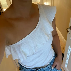 Vit volangtopp - Vit supersöt volangtopp från Stradivarius i strl small! Sparsamt använd :) Köpt i Paris för 2 år sedan. Superfin till ett par jeans eller en fin kjol! Är ej croppad i längden, normal längd.