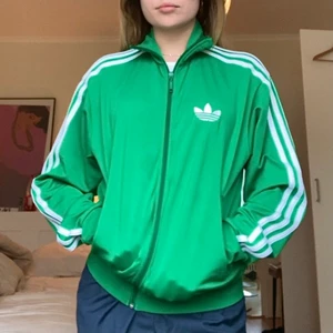 Adidasjacka grön strl S/M - Grön adidasjacka med kritvita ränder på sidorna, retrovariant! Inköpt i USA, nästan aldrig använd. Strl S i herrstorlek, skulle säga M/L för tjejer. Frakt ingår! 🍀☘️