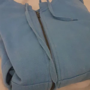 Hoddie - En blå hoddie med dragkedja och en ficka fram, köparen står för frakten