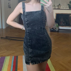 Svart jeansklänning - Säljer denna svart/gråa klänning från H&M. Oanvänd endast testad. Storlek 38. Knappar hela vägen ner.