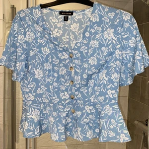 Blå blus - Säljer den här söta toppen i storlek S💙den kommer ifrån Qud London och är aldrig använd(lapp/extra knappar kvar). Skicka privat för fler bilder och köparen står för frakten!💙🤗