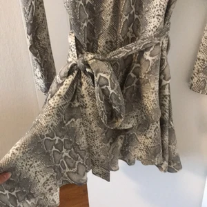 Klänning ginatricot - Sommarklänning från Ginatricot i storlek 38. Har ett bälte rint midjan (går att ta bort). Omlottdesign. Volanger nere vid klänningen. Mycket bra skick 