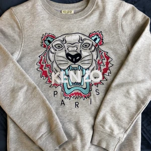 Kenzoparis - Grå kenzotröja köpt från barnavdelningen i NK. Har även kvitto. Säljer tröjan eftersom den är för liten för mig. Tröjan är i väldigt bra skick. Skriv till mig vid intresse🤍✨