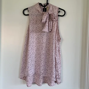 Rosa blus med knytdetalj - En helt oanvänd rosa topp / blus i satin med stjärnor och knytdetalj vid halsen. Dragkedja i nacken. Storlek S/M