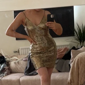 Guldig klänning med paljetter stl S - Guldig klänning med paljetter från Rebecca Stella. Hur fin som helst men får aldrig ett tillfälle att använda den. Öppen rygg. Köpt för 599kr och använd en gång. Stl S. Köparen står för frakt.